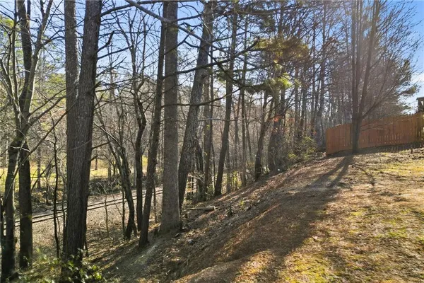 a backyard of a house with large trees and wooden fence
