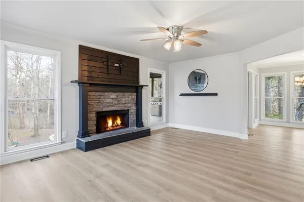 a view of an empty room with wooden floor fireplace and a window