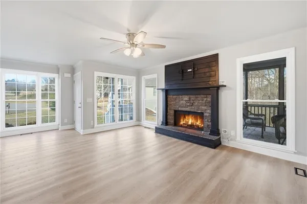 a view of an empty room with wooden floor fireplace and a window