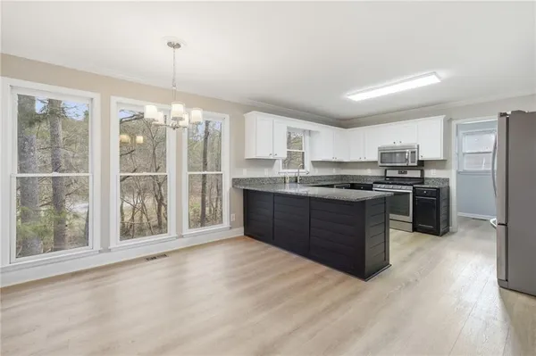 a kitchen with stainless steel appliances granite countertop a stove a sink dishwasher a refrigerator and a cabinets with wooden floor