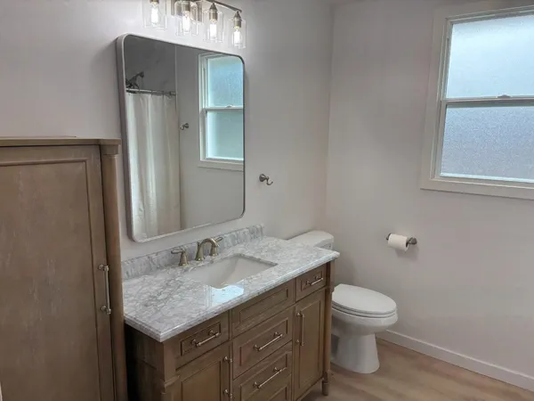 a bathroom with a granite countertop toilet sink and mirror