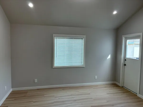 an empty room with wooden floor and windows