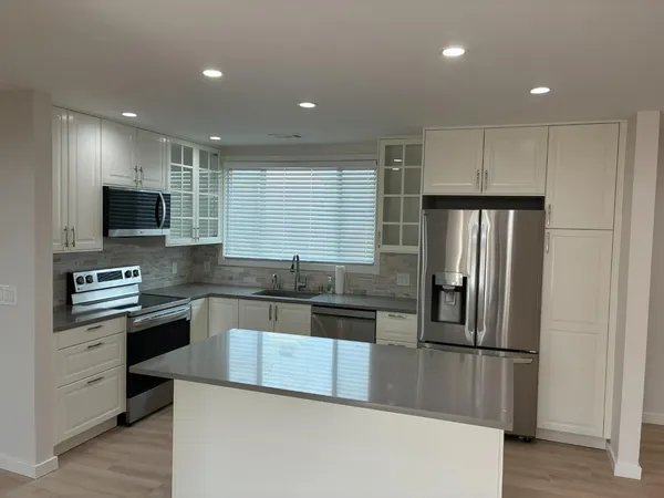 a kitchen with stainless steel appliances granite countertop a refrigerator a stove a sink a microwave a counter space and cabinets