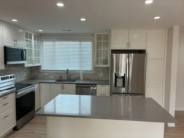 a kitchen with stainless steel appliances granite countertop a stove a sink a refrigerator and a microwave