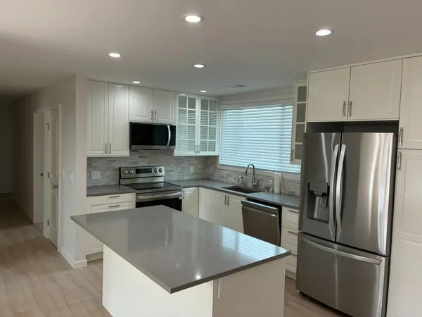 a kitchen with stainless steel appliances granite countertop a refrigerator a sink a stove a microwave and a refrigerator