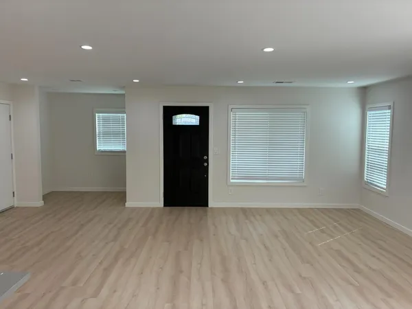 an empty room with wooden floor and windows