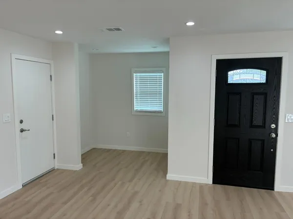 a view of an empty room with wooden floor and closet
