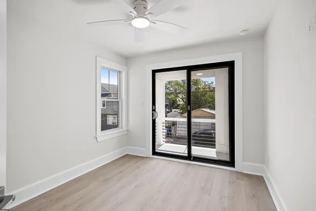 an empty room with wooden floor fan and windows