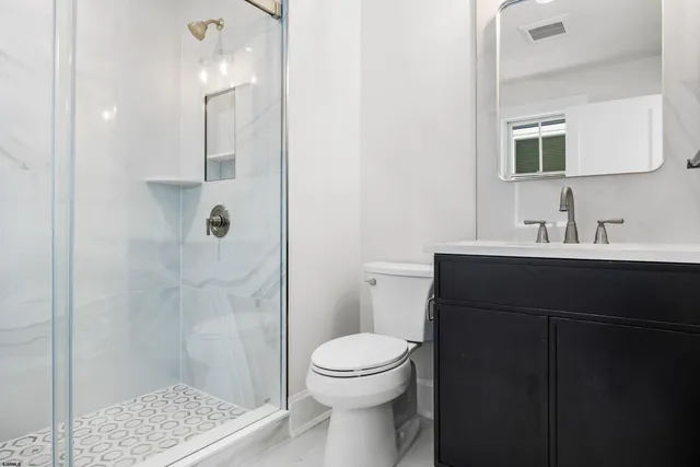 a bathroom with a sink a toilet a shower and a mirror