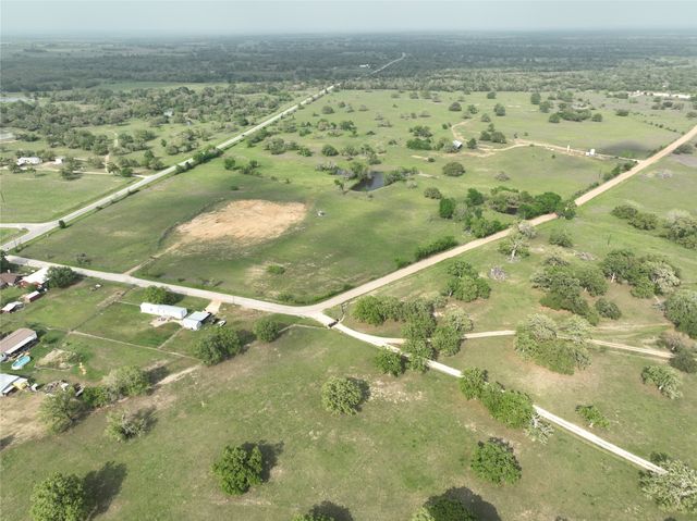 a view of a green field with lots of buildings in the background
