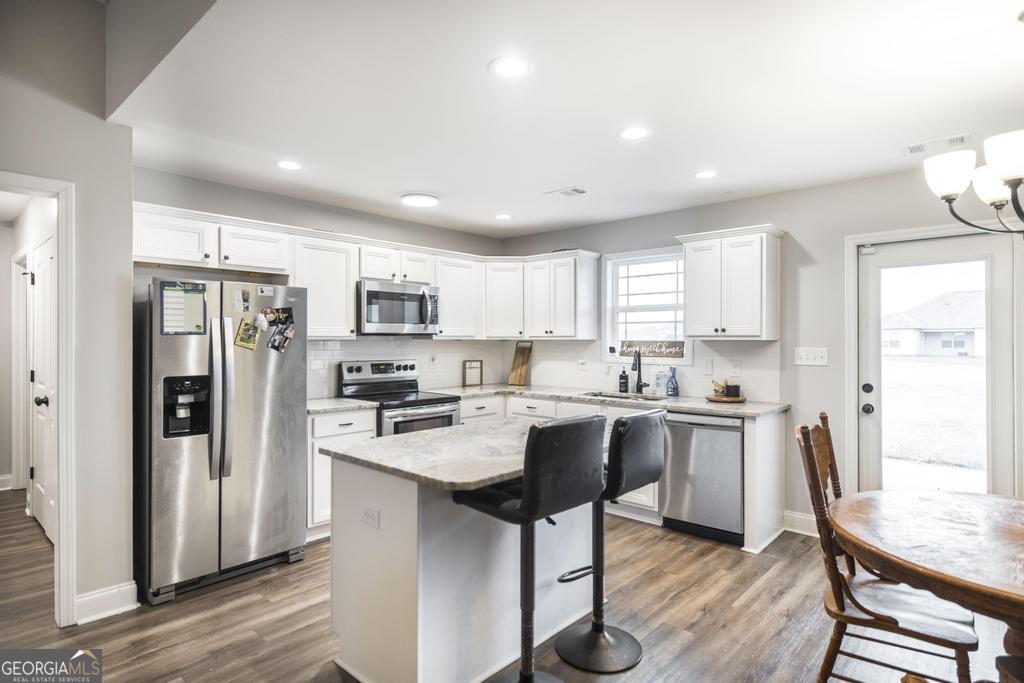 137 Sadie Heights Boulevard Perry, GA 31069 - Photo 8 of 25 a kitchen with stainless steel appliances granite countertop a refrigerator a sink dishwasher a stove and white appliances with wooden floor