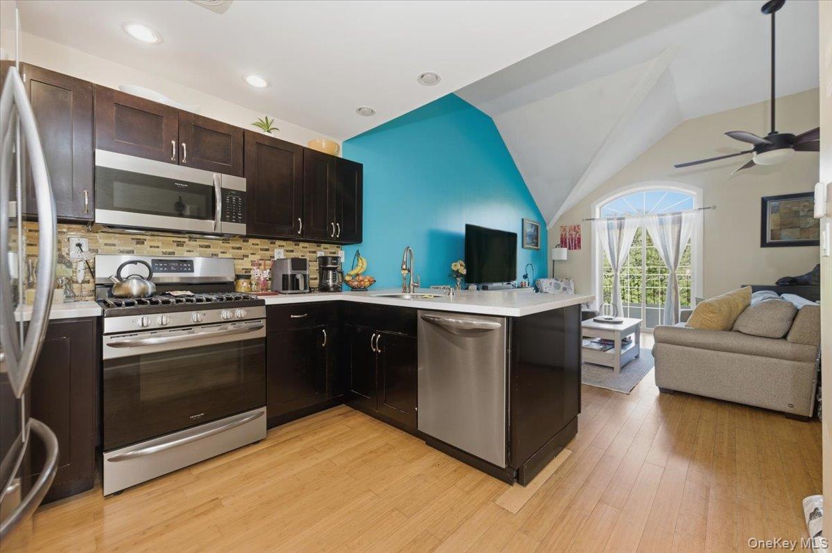 2853 Ely Avenue, Unit 3 Bronx, NY 10469 - Photo 19 of 20 a kitchen with stainless steel appliances kitchen island granite countertop a stove top oven a sink dishwasher a dining table and chairs with wooden floor