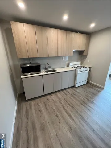 a kitchen with stainless steel appliances granite countertop a sink a stove and a wooden floors