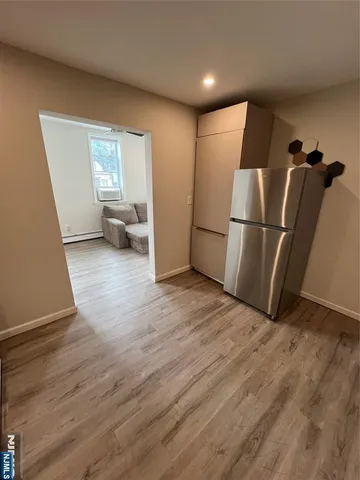 a view of a livingroom with wooden floor and a refrigerator
