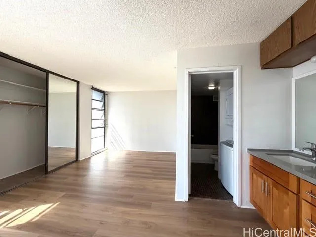 a view of an empty room with wooden floor and closet