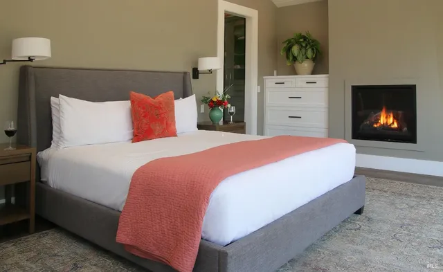 a bed sitting in a bedroom next to a lamp next to a window and a fireplace