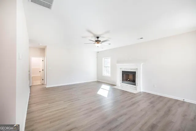 an empty room with a fireplace and a ceiling fan