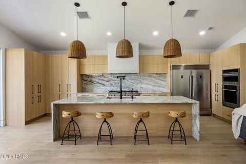 a kitchen with stainless steel appliances granite countertop a sink a stove and a wooden floors