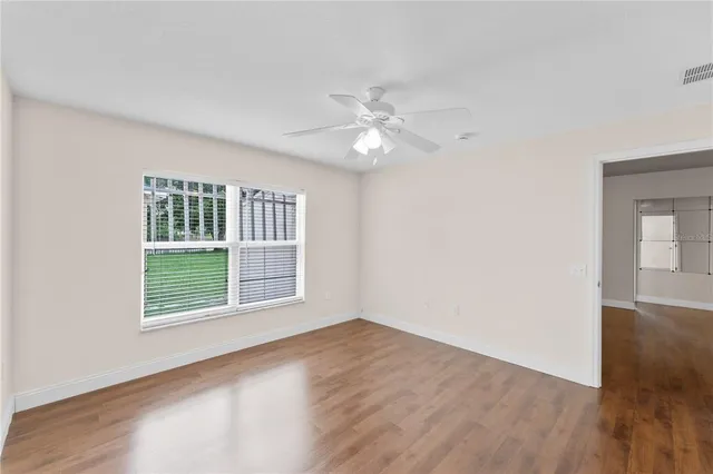 a view of an empty room with wooden floor and a window
