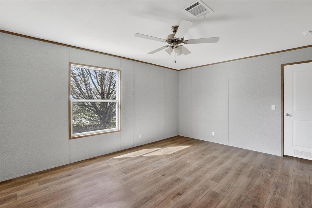 206 Rhett Court Aurora, TX 76078 - Photo 20 of 40 an empty room with wooden floor fan and windows