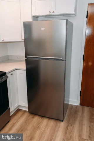 a view of a refrigerator in kitchen and an empty room