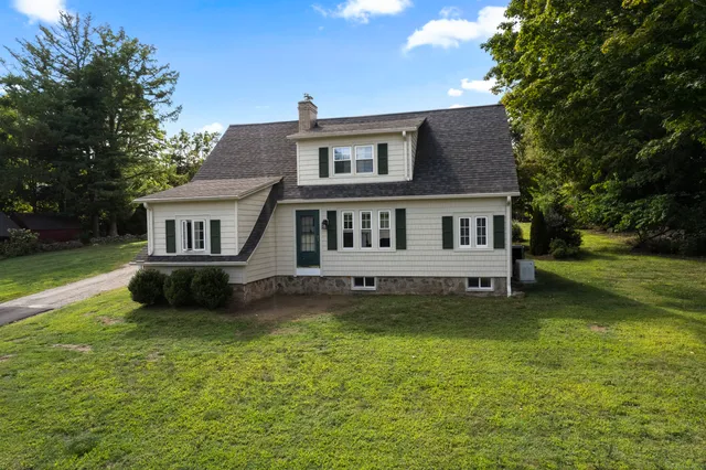 a view of a house with a yard deck and a large tree