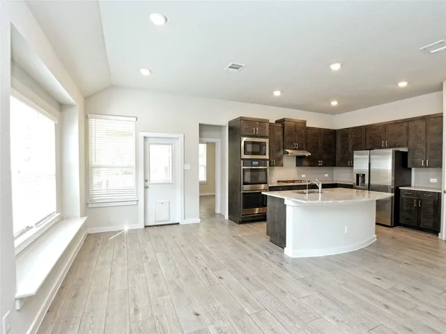 a kitchen with stainless steel appliances kitchen island granite countertop a stove top oven and refrigerator