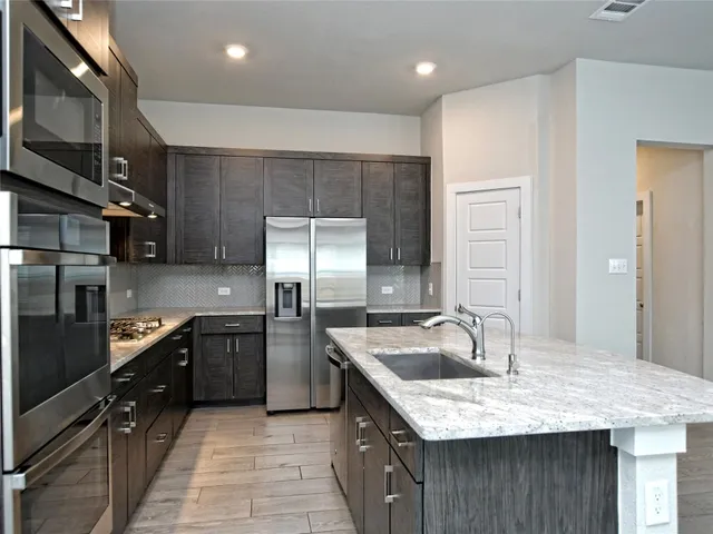 a kitchen with stainless steel appliances granite countertop a sink stove and refrigerator