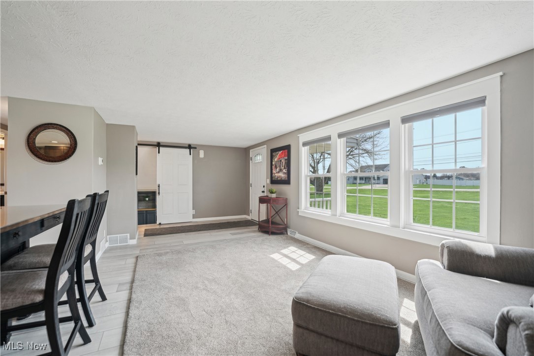 15415 Mason Road Vermilion, OH 44089 - Photo 3 of 50 Living area featuring a textured ceiling, visible vents, light wood finished floors, baseboards, and a barn door