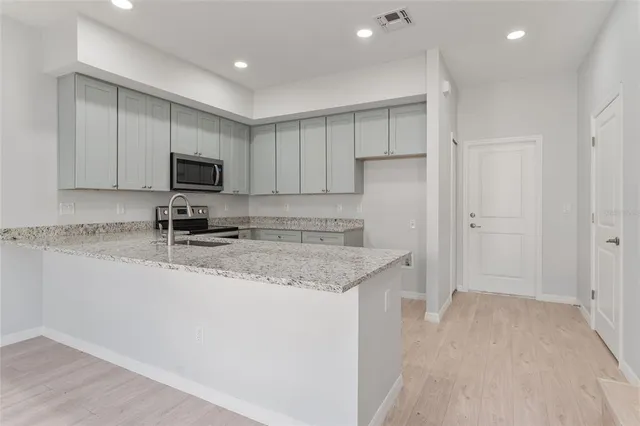 a kitchen with kitchen island granite countertop a sink a stove a refrigerator and cabinets