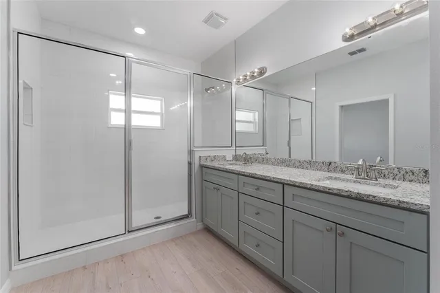 a bathroom with a granite countertop double vanity sink and mirror