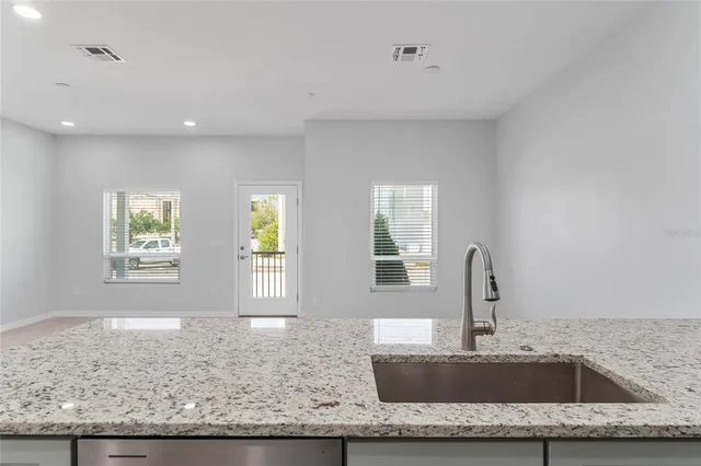 a kitchen with granite countertop a sink and white cabinets