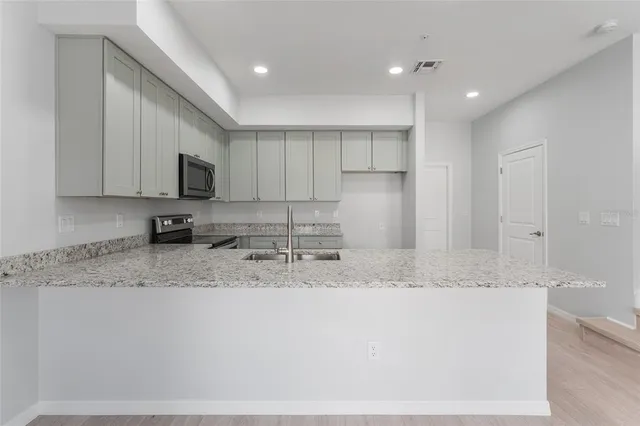 a kitchen with stainless steel appliances granite countertop a sink a stove a microwave a sink and white cabinets