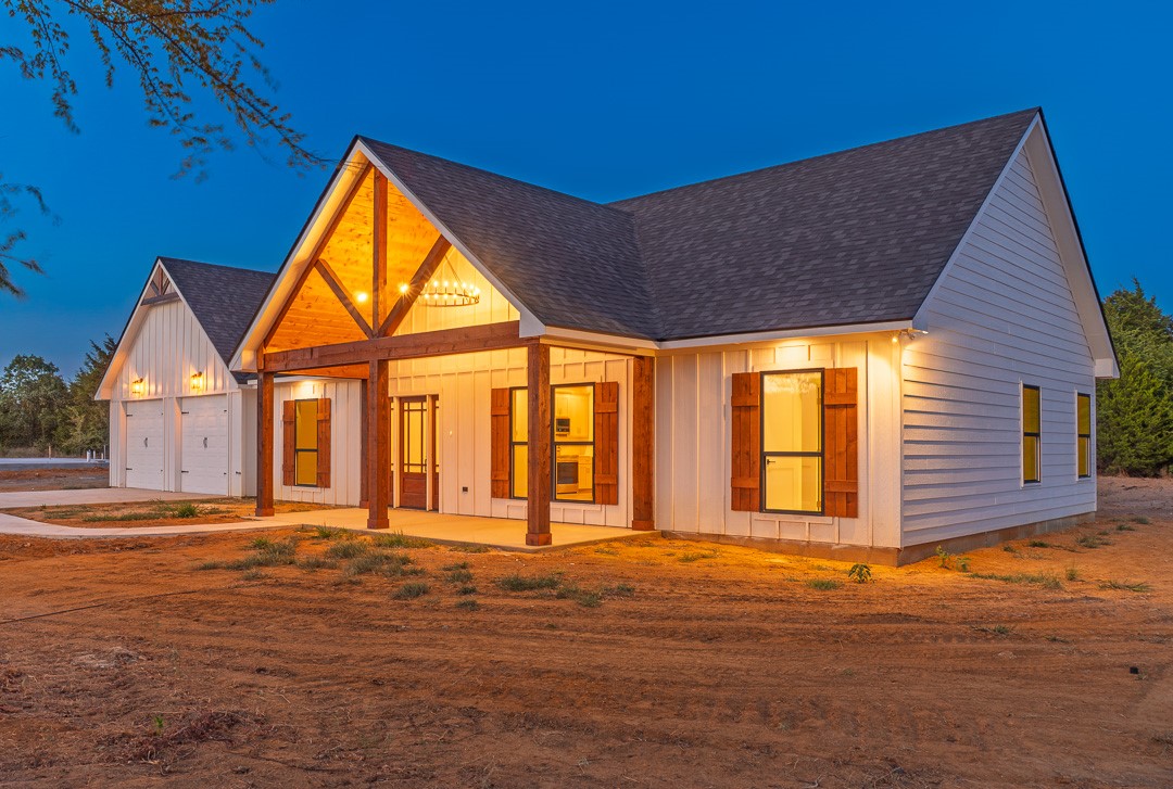 205 Blessings Way Colbert, OK 74733 - Photo 3 of 24 Board and batten and horizontal siding exterior with a covered front porch featuring exposed wood beams, a two-car garage, and dark-paneled window shutters