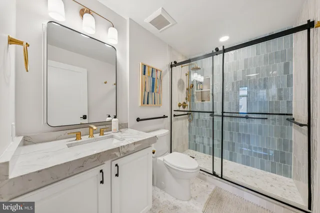 a bathroom with a shower sink vanity mirror and toilet