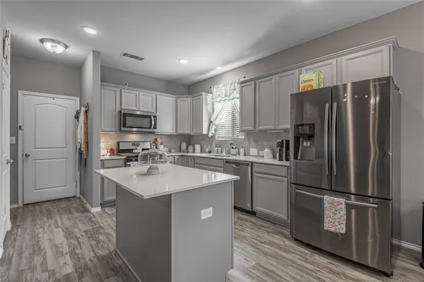 a kitchen with a refrigerator a sink cabinets and wooden floor