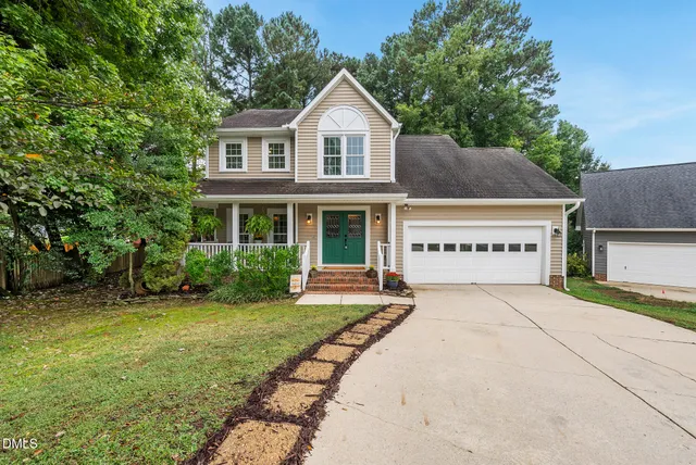 a view of a house with a yard and large tree