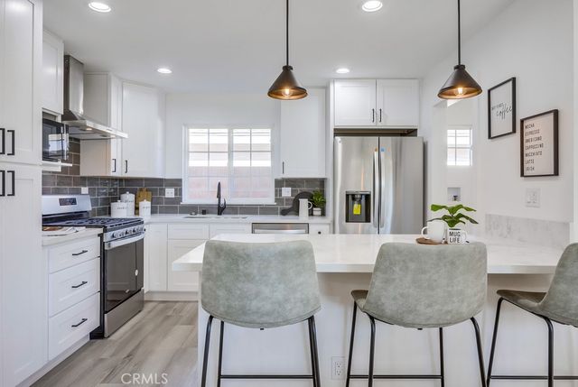 a kitchen with stainless steel appliances granite countertop a stove a sink a refrigerator a kitchen island a stove and a cabinets