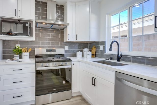 a kitchen with stainless steel appliances granite countertop a stove and white cabinets