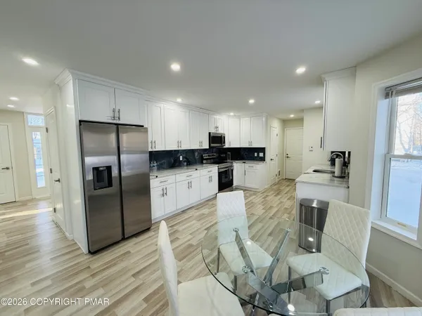 a kitchen with stainless steel appliances granite countertop a refrigerator a stove a sink a dining table and chairs