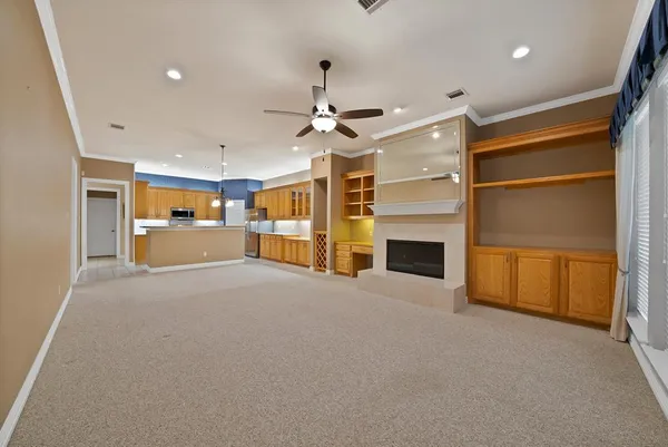 a view of a livingroom with a fireplace a ceiling fan a kitchen refrigerator and a fireplace