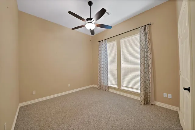 an empty room with a ceiling fan and window