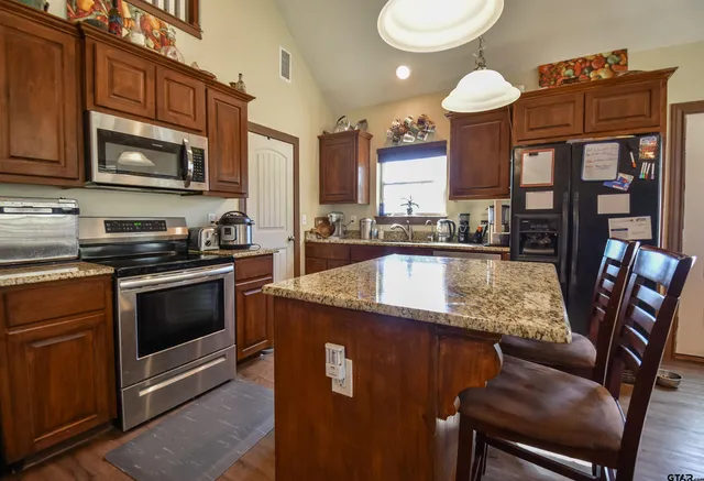 a kitchen with stainless steel appliances granite countertop a sink a stove counter space and cabinets