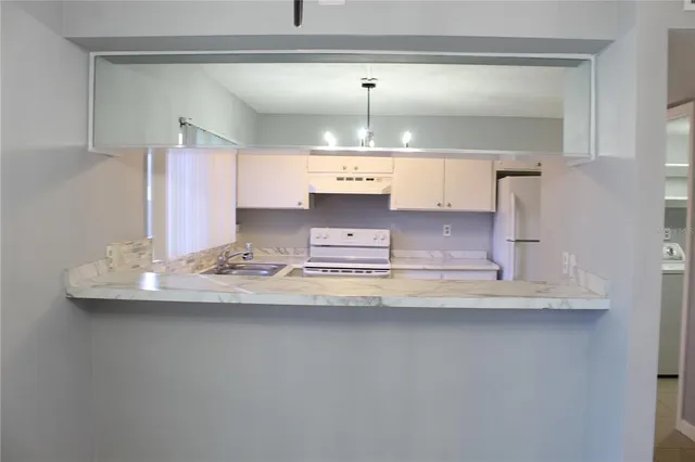 a kitchen with kitchen island white cabinets and refrigerator