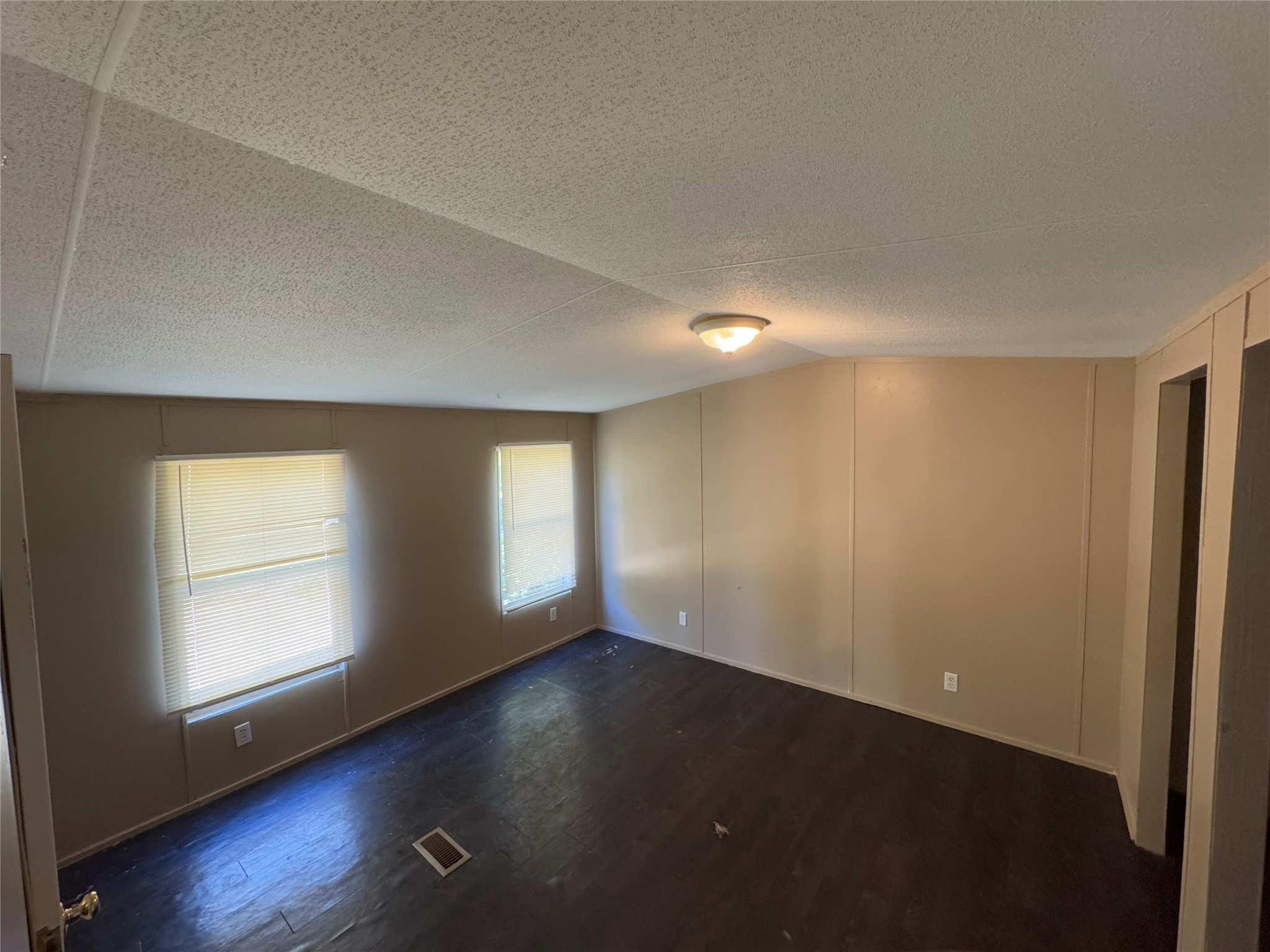 8315 Burleson Manor Road, Unit B Manor, TX 78653 - Photo 7 of 15 Unfurnished room with dark wood finished floors, a textured ceiling, and a decorative wall