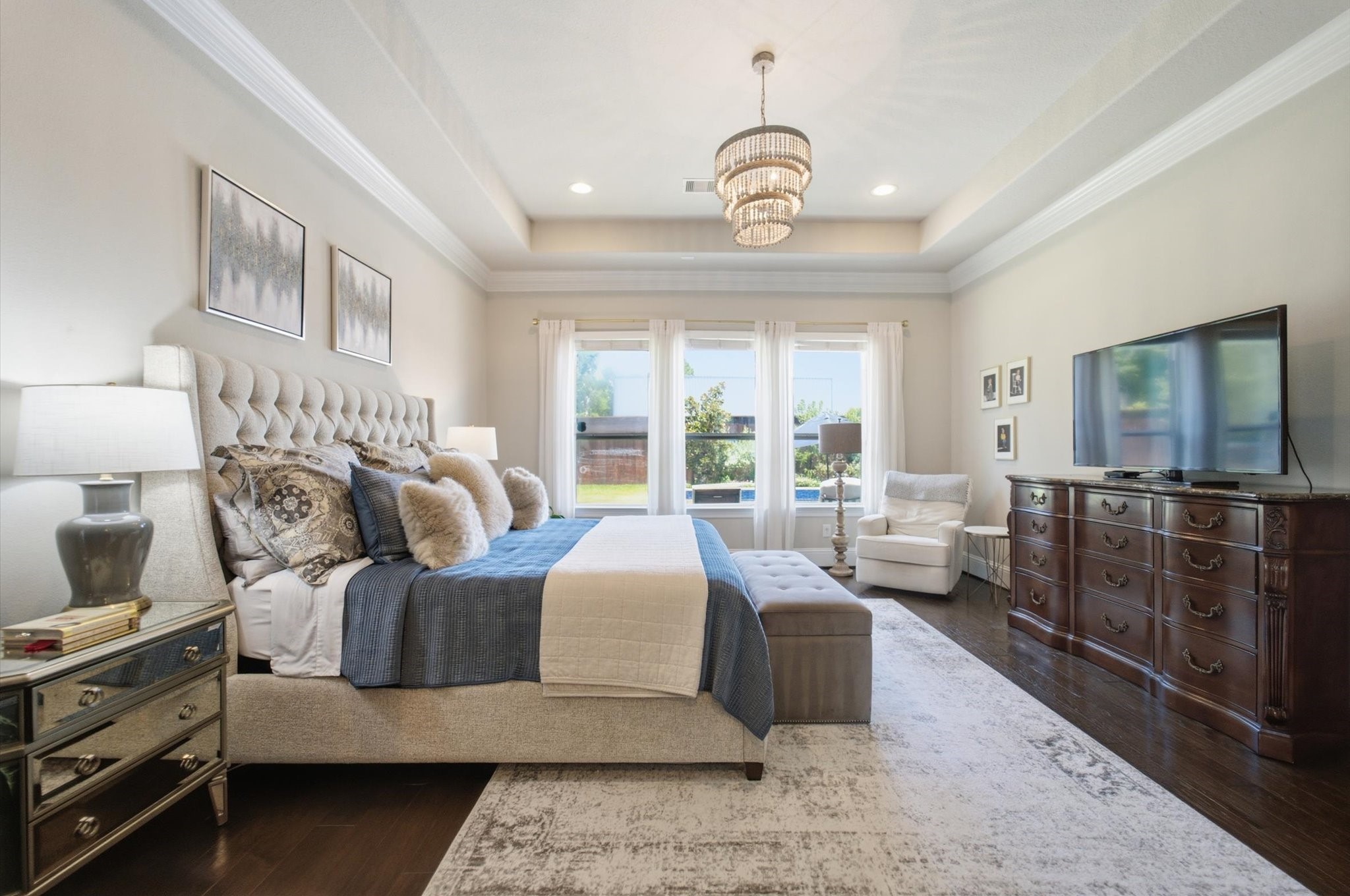 23722 Thortons Park Lane Spring, TX 77389 - Photo 11 of 48 This spacious bedroom features elegant tray ceilings, a plush upholstered bed, and abundant natural light from large windows. The room is complemented by a chic chandelier, a cozy seating area, and stylish decor.