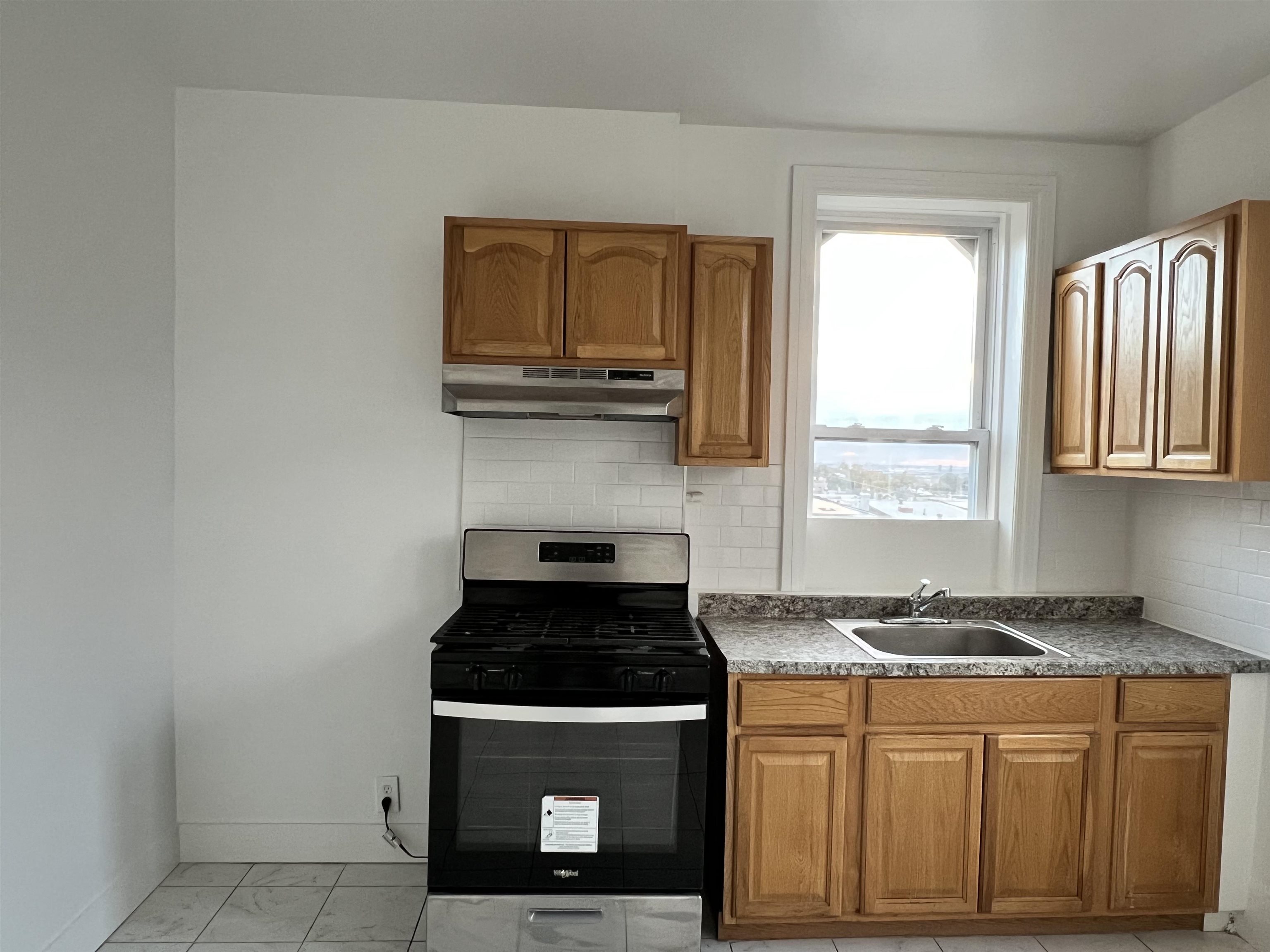 1201 John F. Kennedy Boulevard, Unit 4 North Bergen, NJ 07047 - Photo 2 of 13 a kitchen with granite countertop a stove a sink and a microwave