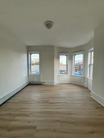 a view of an empty room with window and wooden floor