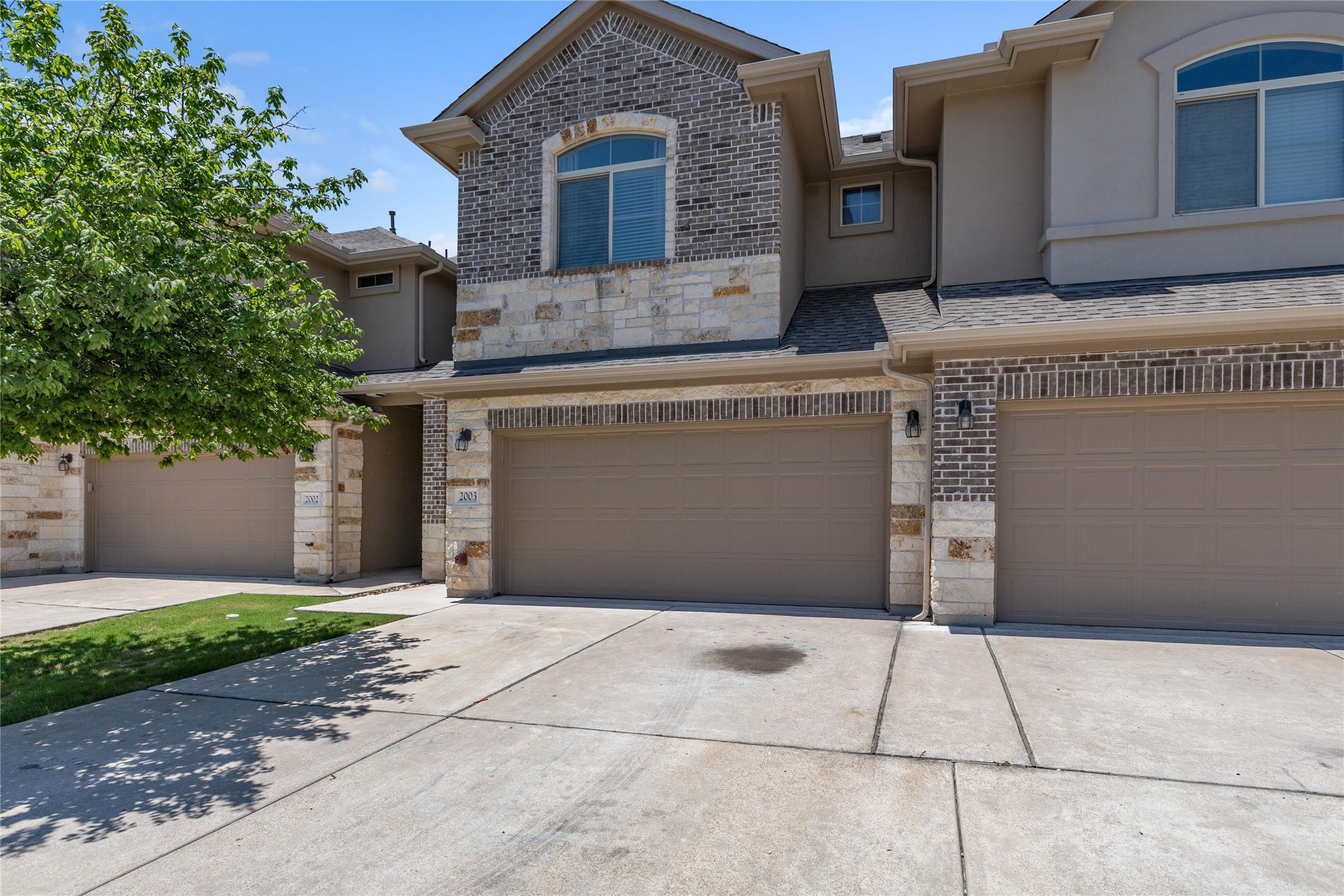 2880 Donnell Drive, Unit 2003 Round Rock, TX 78664 - Photo 2 of 31 Multi-family residence featuring a brick and stone facade, arched windows, and individual garages