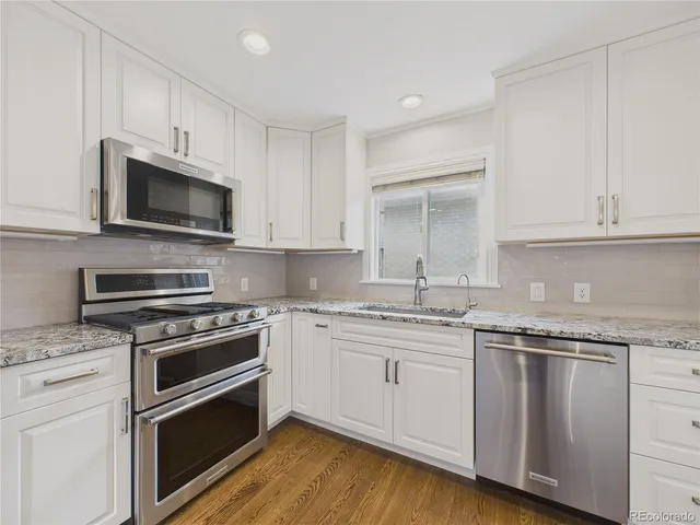 a kitchen with granite countertop white cabinets and stainless steel appliances